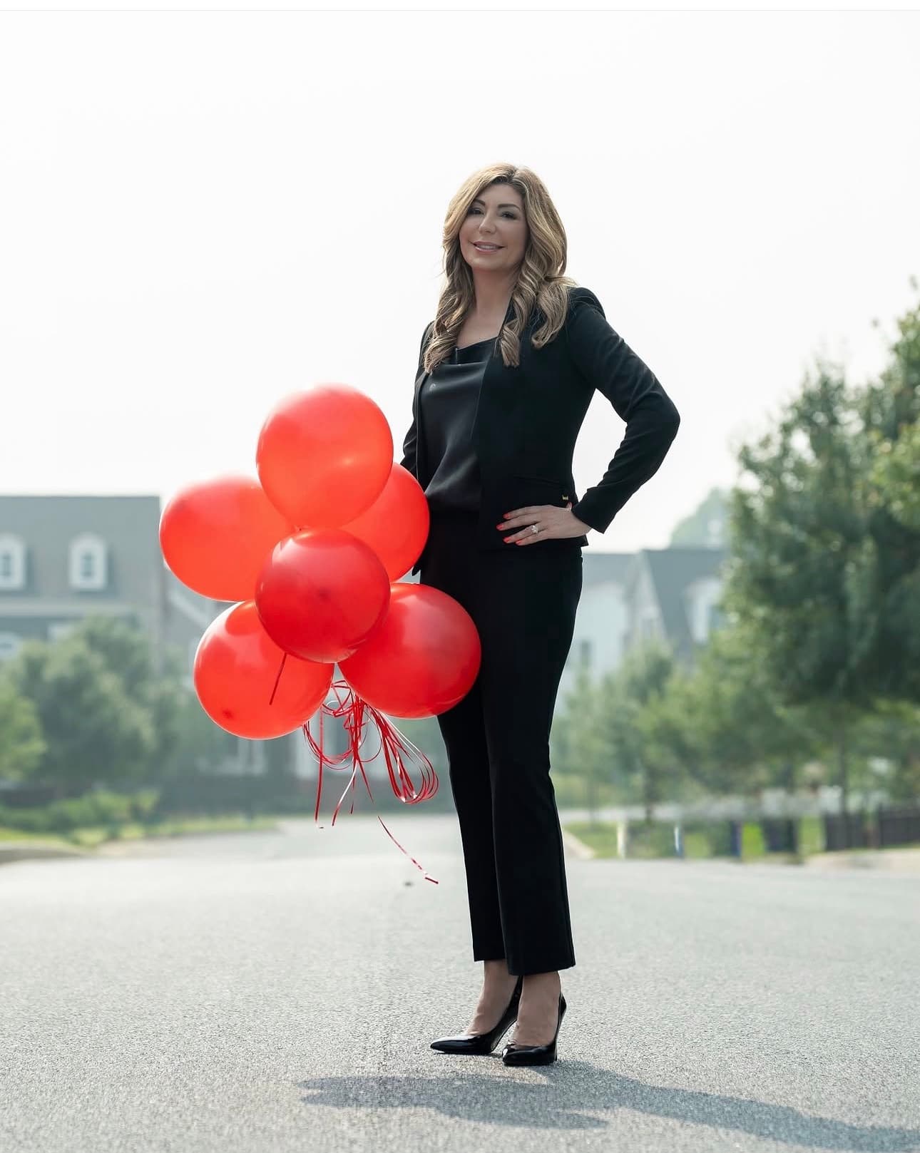 Danielle Halstuch holding red balloons in a Maple Lawn neighborhood