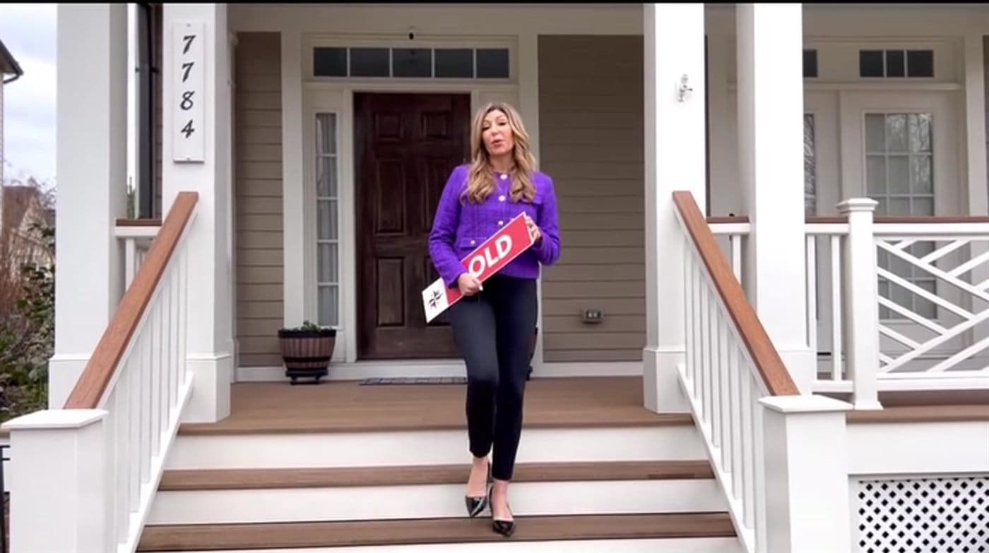 Danielle Halstuch with a SOLD sign on the porch of a Fulton home